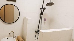 A bathroom with a sink, mirror, and a shower with a handheld showerhead. - Hotel KEUR HORUS (St. Louis)