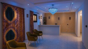 A lobby with a reception desk, a chandelier, and three chairs. - Hotel KEUR HORUS (St. Louis)