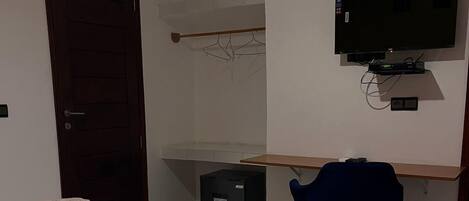 A bedroom with a bed, a desk, a chair, a TV, and a wardrobe.
