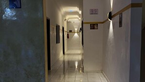 A hotel corridor with marble flooring, a ceiling light, and a sign indicating no smoking. - Hotel KEUR HORUS (St. Louis)