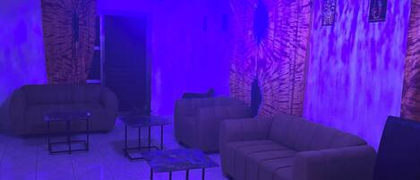 A room with a chandelier, sofas, and a patterned wall.