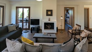 Un salon comprenant un canapé, une table basse, une cheminée, un téléviseur et un coin repas avec des chaises.