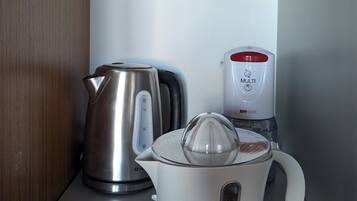 A kitchen with a kettle, a coffee maker, and a water dispenser on a countertop.