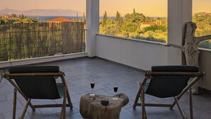 Un balcon avec deux fauteuils en osier, une petite table en bois et une vue sur un paysage montagneux.