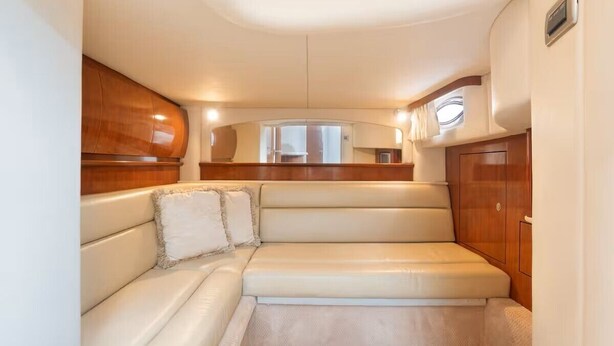 Un interior compacto y bien iluminado con una zona de estar acolchada, paneles de madera y un ventanal.