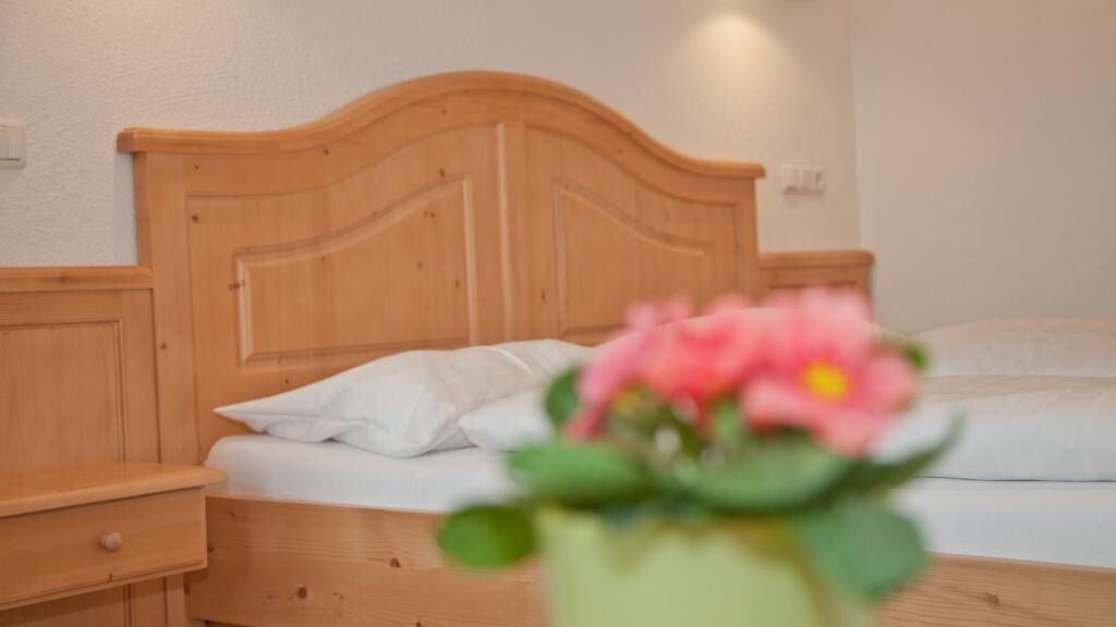 Ein Schlafzimmer mit einem hölzernen Kopfteil, einem weißen Bett und einem Nachttisch mit einer Schublade.