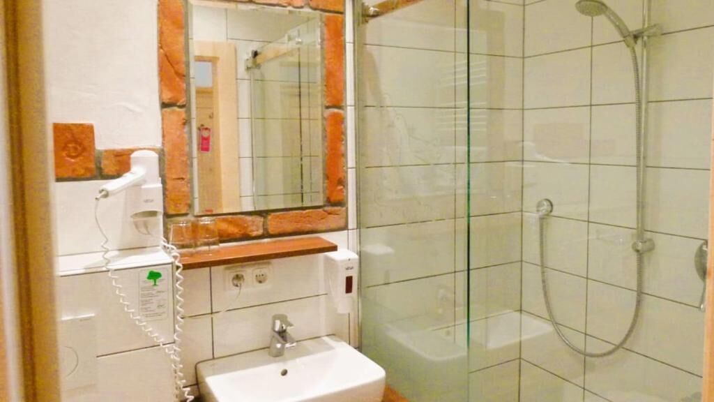 A bathroom with a sink, mirror, and shower.