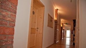 Un couloir avec des portes en bois, un mur en briques et un tableau encadré accroché au mur.