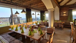 Un restaurant avec des tables et des chaises en bois, des serviettes vertes et une vue sur un terrain de sport.