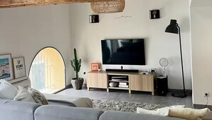 A modern living room with exposed wooden beams, a large flat-screen TV, a potted plant, and a cozy sofa. - Magnificent Loft near town center (Saint-Chamas)
