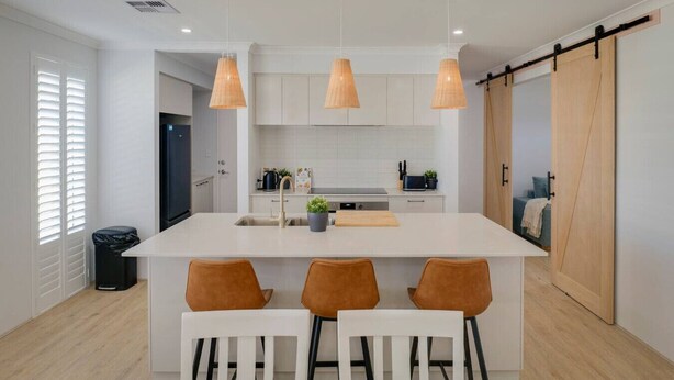 A modern kitchen with a central island, pendant lights, and a sliding barn door. - Nessie`s Nook Relax in fully Air-Conditioned Style (Dunsborough)