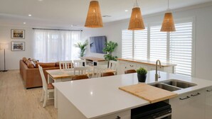 A modern kitchen with a central island, white cabinetry, and pendant lighting. - Nessie`s Nook Relax in fully Air-Conditioned Style (Dunsborough)