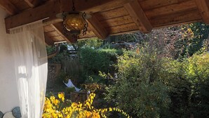 Une terrasse en bois avec des meubles en osier, une table et des chaises.