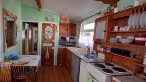 A compact kitchen with wooden cabinets, a microwave, and a stove. - 3 Bed Chalet - Sleeps 6 - Parking - Garden - Wifi (Great Yarmouth)