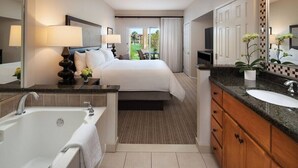 Ein Hotelzimmer mit einem großen Bett, einem separaten Badezimmer mit Badewanne, einem Waschtisch und einem großen Spiegel.