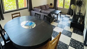 A room with a round dining table, a sofa, and a window with curtains. - Villa Six-Fours (Six-Fours-les-Plages)