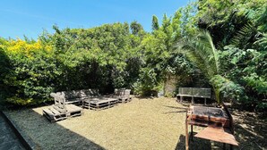 An outdoor seating area with wooden benches and tables, surrounded by dense greenery and trees. - Villa Six-Fours (Six-Fours-les-Plages)