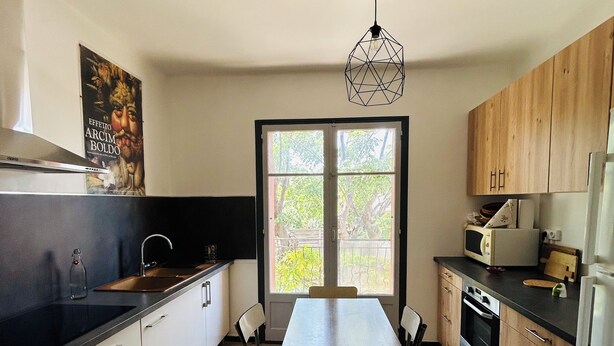 A compact kitchen with a dining table, chairs, a sink, a stove, and cabinets. - Villa Six-Fours (Six-Fours-les-Plages)