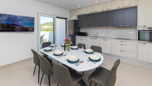A modern kitchen with dark cabinets, a built-in oven, and a dining area with a table set for four.