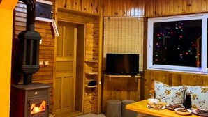 A cozy room with a wood-burning stove, a television, and a dining area with a table set for a meal.