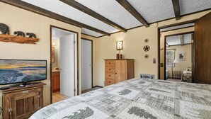 A bedroom with a large bed, wooden dresser, and a television on a stand. - Cabin in the Pines (Big Bear Lake)