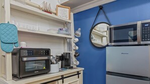 Una cocina con horno Joyoung, refrigerador Hisense, microondas y pared azul.