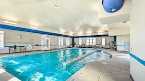 An indoor swimming pool with clear water, a diving board, and lounge chairs along the walls. - TPV - Palazzo Di Amore - BRAND NEW - Luxury Living (Durham)