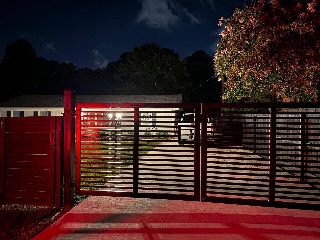 A gated entrance with a red gate and a metal fence.