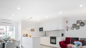 Eine moderne Küche mit weißen Schränken, einem roten Sofa und dekorativen Tellern an der Wand.