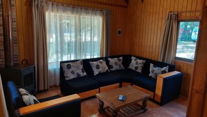 Ett mysigt vardagsrum med en hörnsoffa, ett soffbord i trä och en öppen spis.