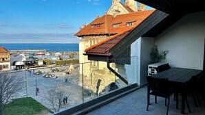 Uma varanda com vista para um porto, um restaurante e edifícios históricos.