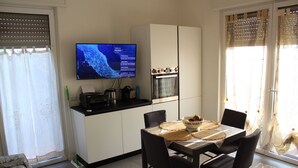 Een moderne keuken met een flatscreen televisie, een eettafel met stoelen en een raam met gordijnen.