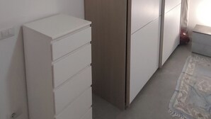 Een kamer met een witte garderobe, een witte dressoir en een kamerkleed met dessin.
