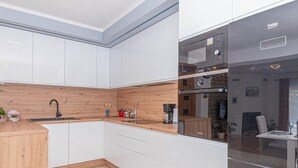 Cozinha moderna com armários brancos, bancada de madeira, forno embutido e geladeira.