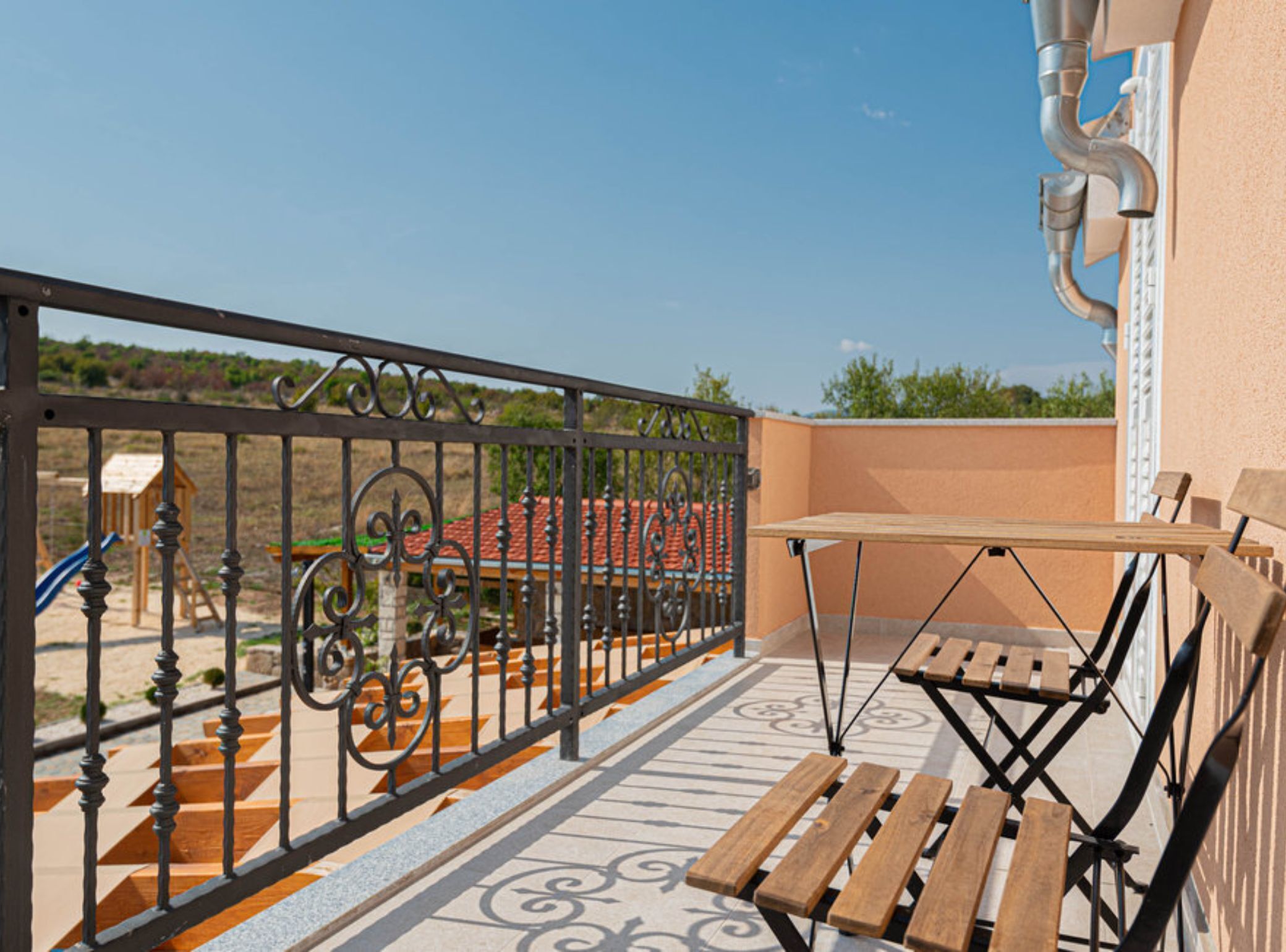 A balcony with a metal railing, a wooden table, and a bench.