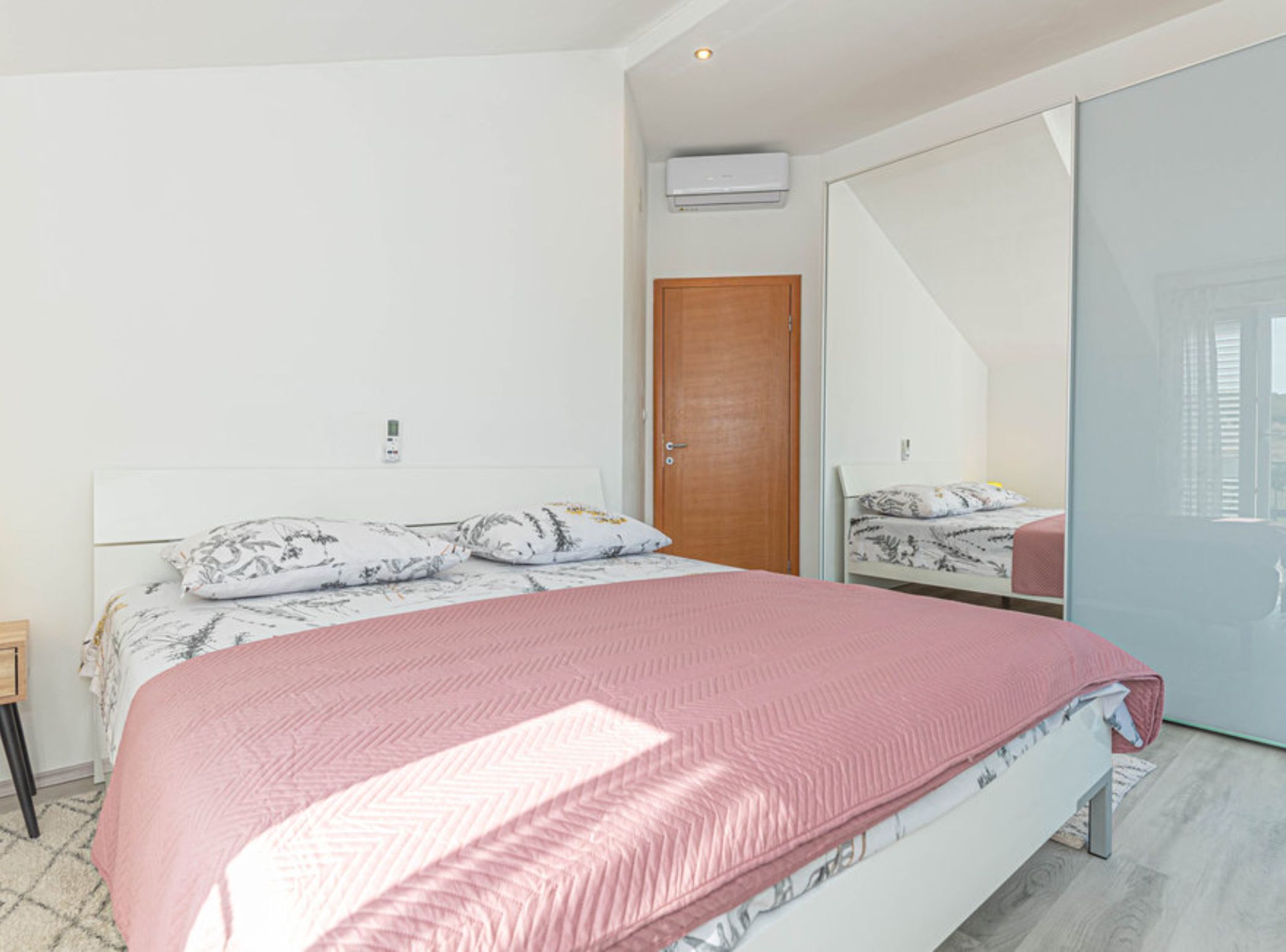 Ein Schlafzimmer mit einem Bett, einer Holztür und einer Glastür, die auf einen Balkon führt.