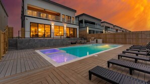 A modern house with a swimming pool, wooden deck, and outdoor furniture. - 4,000 SF Waterfront Home w/ Pool, Sleeps 22 (Port Isabel)