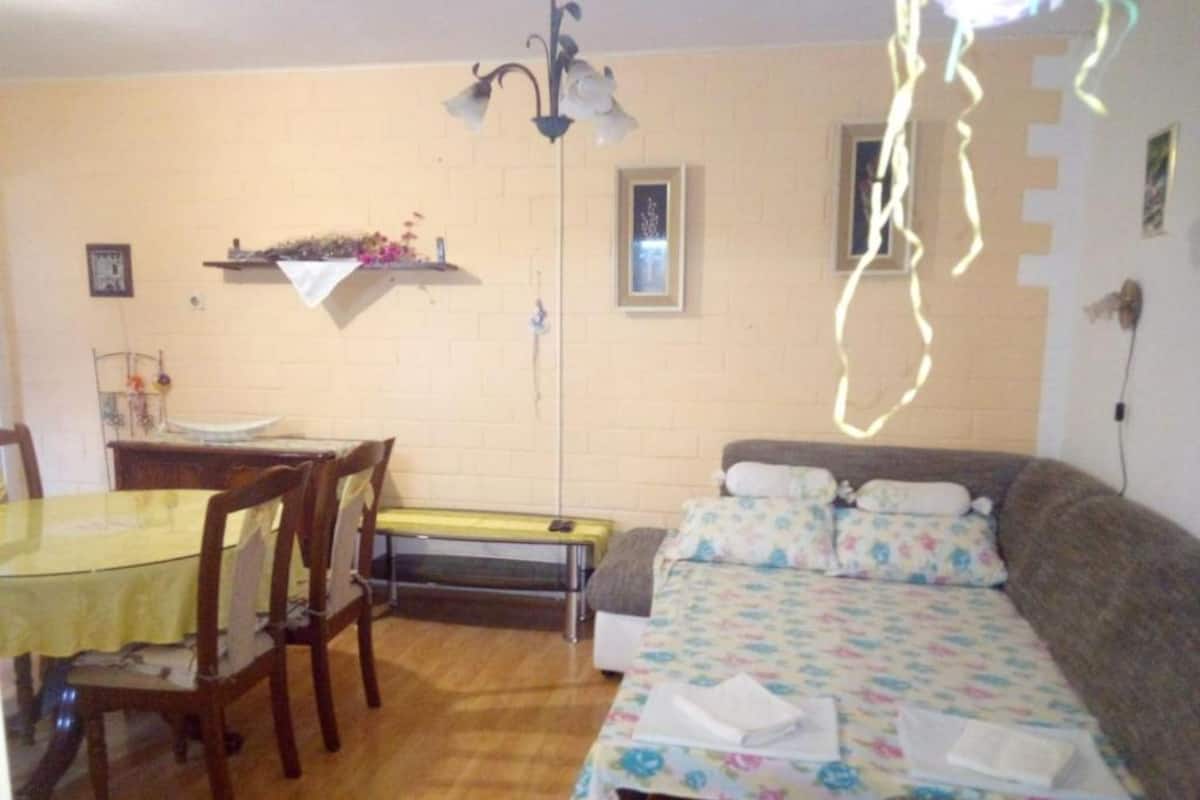 A compact living space with a dining table, chairs, a sofa, and a small kitchen area.
