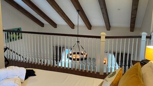 A bedroom with a wooden ceiling, white railing, and a hanging light fixture. - Cozy Upscale Savannah carriage house, walk to all! (Savannah)