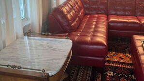 A living room with a red leather sectional sofa, a marble coffee table, and a patterned rug. - Peaceful Meredith Getaway - 2 BR w/ Wifi & Charm (Meredith)