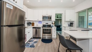 A modern kitchen with white cabinets, stainless steel appliances, and a blue rug.