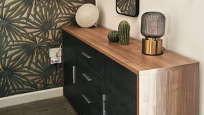 A modern room with a patterned wallpaper, a wooden console table, a wall-mounted phone, and a decorative lamp. - Isensi luxury suite Trani (Trani)