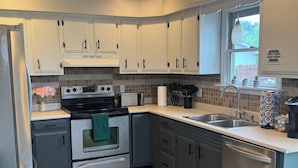 Una cocina moderna con armarios blancos, electrodomésticos de acero inoxidable y salpicadero de azulejos.
