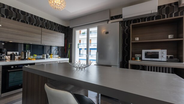 A modern kitchen with a central island, stainless steel appliances, and a view to the balcony.