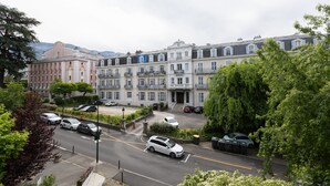 A multi-story building with a central courtyard, surrounded by trees and parked cars.
