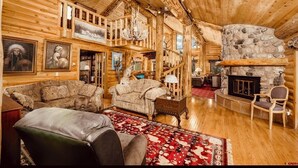 Ein Holzblockhaus-Interieur mit Kamin, Holzwänden und einer gemütlichen Sitzecke.