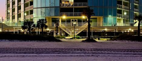 Un hotel de varios pisos con fachada curva, varios balcones y una escalera central que conduce a la entrada.
