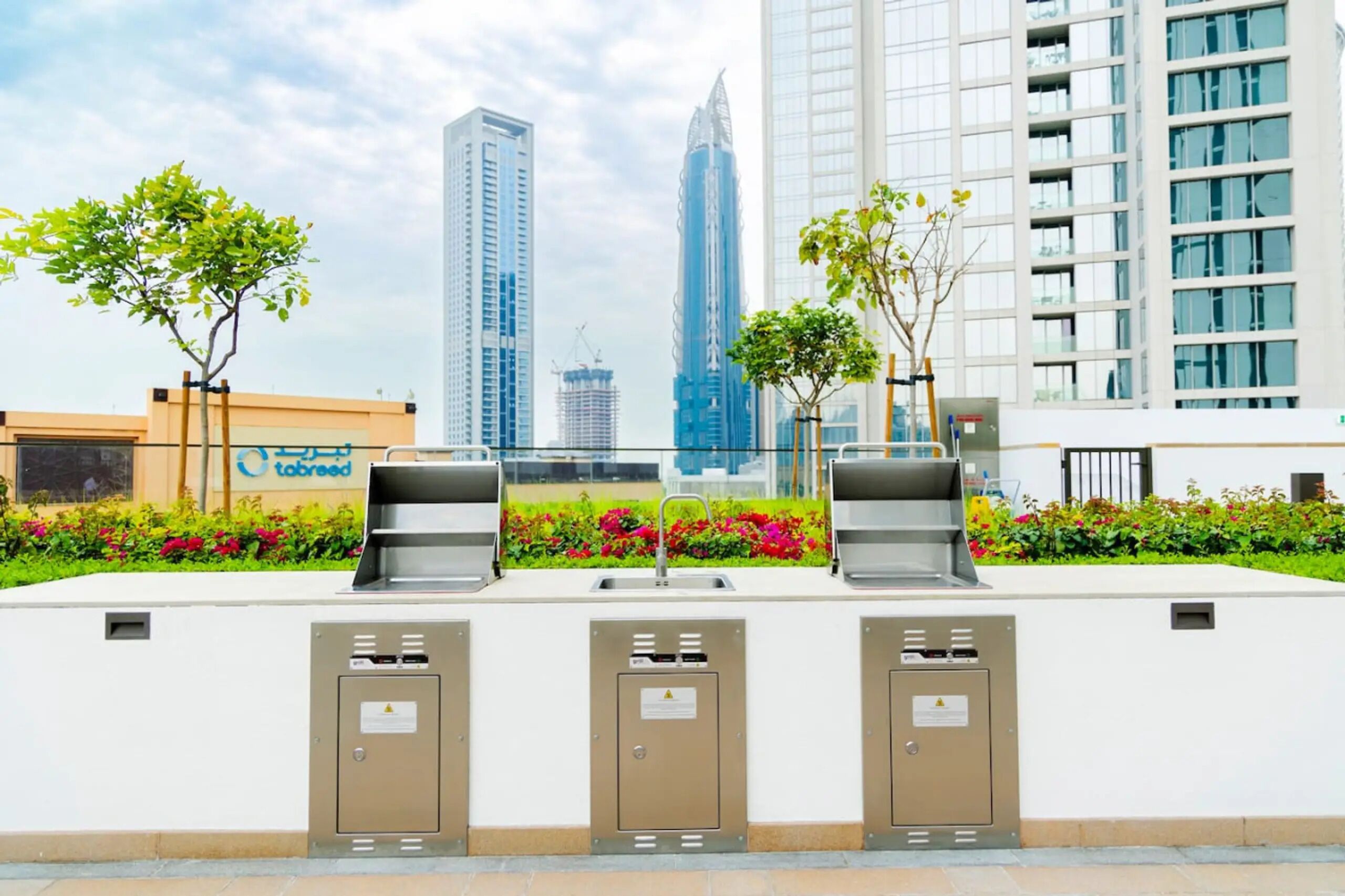 A modern outdoor area with a water fountain, a vending machine, and a trash bin.