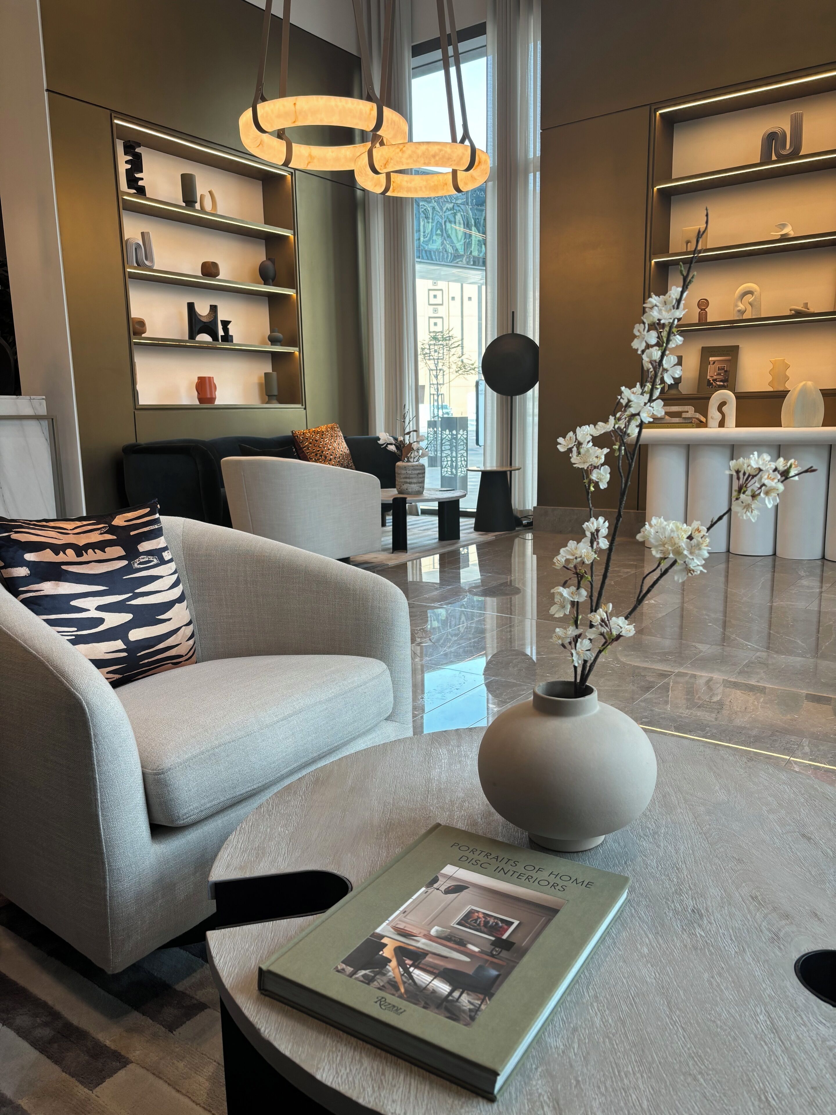 Un salon moderne avec un canapé, une table basse sur laquelle repose un livre et un vase rempli de fleurs.