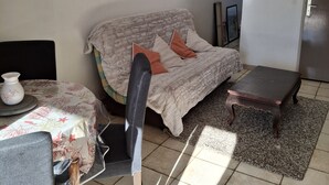 Un salon avec un canapé, une table basse, un ventilateur de plafond et des tableaux encadrés accrochés au mur.